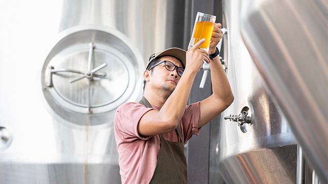 Asian worker inspecting a beer