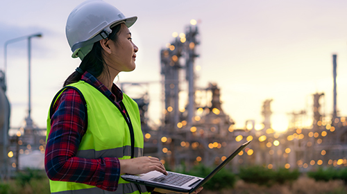 female engineer with laptop outside chemical plant
